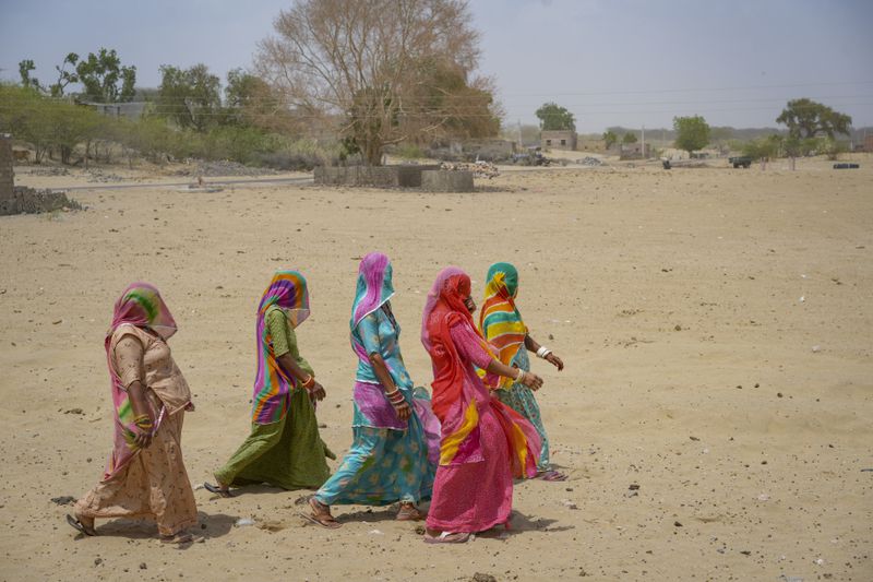 Women walk to cast their vote during the second phase of polling in the six-week long national election in the desert village Akli in western Rajasthan state, India, Friday, April 26, 2024. (AP Photo/Deepak Sharma)