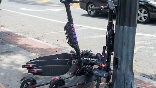 Electric scooters sit piled up on the sidewalk near Centennial Olympic Park in Atlanta. (Alyssa Pointer/alyssa.pointer@ajc.com)