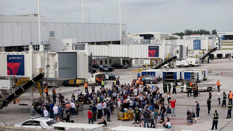 People stand on the tarmac at the Fort Lauderdale-Hollywood International Airport after a shooter opened fire inside a terminal of the airport, killing several people and wounding others before being taken into custody, Friday, Jan. 6, 2017, in Fort Lauderdale, Fla. (AP Photo/Wilfredo Lee)