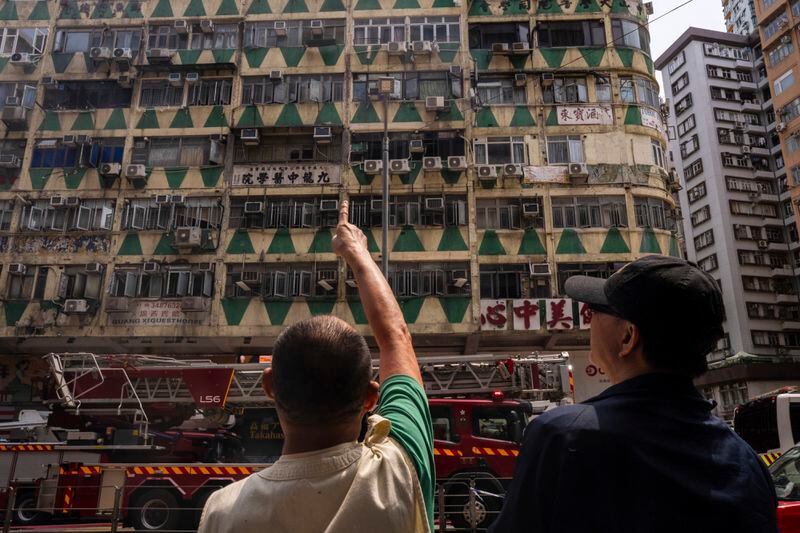 Onlookers stand near a building called New Lucky House where a fire started in Hong Kong, Wednesday, April 10, 2024. (AP Photo/Louise Delmotte)