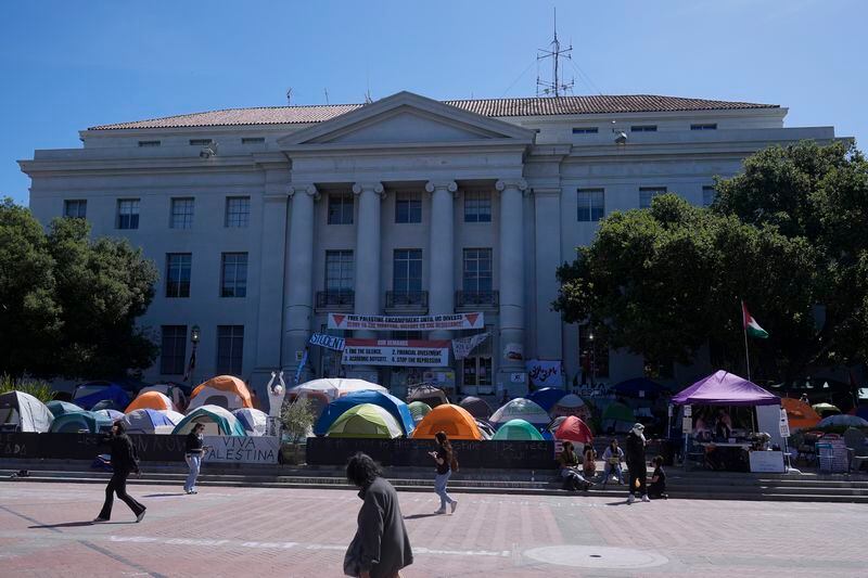 FILE - People walk past tents set up in front of Sproul Hall at UC Berkeley in Berkeley, Calif., Thursday, May 2, 2024. The only thing more American than protests for a cause? Wanting them to pipe down and go away. From the Boston Tea Party to the Civil Rights Movement to last week, U.S. history is filled with the tension between people demonstrating about issues that matter to them and others who want to be left alone. (AP Photo/Jeff Chiu, File)