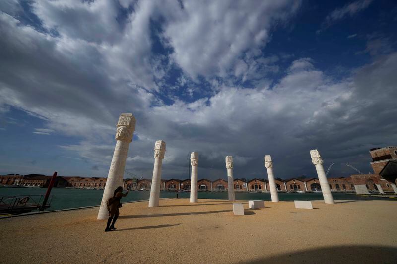 A visitor looks the installation 'Keepers of the krown' by artist Lauren Halsey, at the Arsenale, during the 60th Biennale of Arts exhibition in Venice, Italy, Tuesday, April 16, 2024. The Venice Biennale contemporary art exhibition opens Saturday for its six-month run through Nov. 26. The main show titled 'Stranieri Ovunque – Foreigners Everywhere,' is curated for the first time by a Latin American, Brazilian Adrian Pedrosa. Pedrosa is putting a focus on underrepresented artists from the global south, along with gay and Indigenous artists. Alongside the main exhibition, 88 national pavilions fan out from the traditional venue in Venice's Giardini, to the Arsenale and other locations scattered throughout the lagoon city. (AP Photo/Luca Bruno)