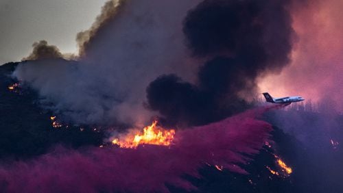 A DC-10 air tanker drops fire retardant on the Holy fire burning in Cleveland National Forest above homes in Lake Elsinore, Calif., on Tuesday, on Aug. 7, 2018. (Allen J. Schaben/Los Angeles Times/TNS)
