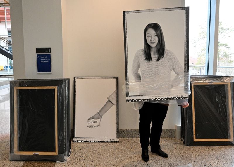 Sara Tanner, executive director of communications and strategic initiatives, unwraps a portrait of Joanne Williams, featured in Emory University's new mental health campaign, before the photograph is installed in the student center on Thursday, Feb. 8, 2024, in Atlanta. (Hyosub Shin / Hyosub.Shin@ajc.com)