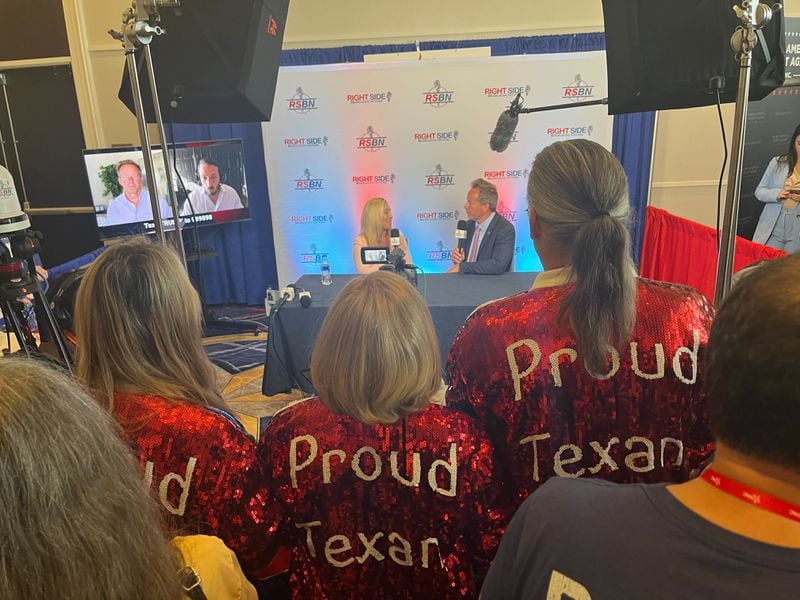 Melissa Cornwell, left, and others wearing the same "Proud Texan" jacket, listen to U.S. Rep. Marjorie Taylor Greene as she is interviewed at CPAC.