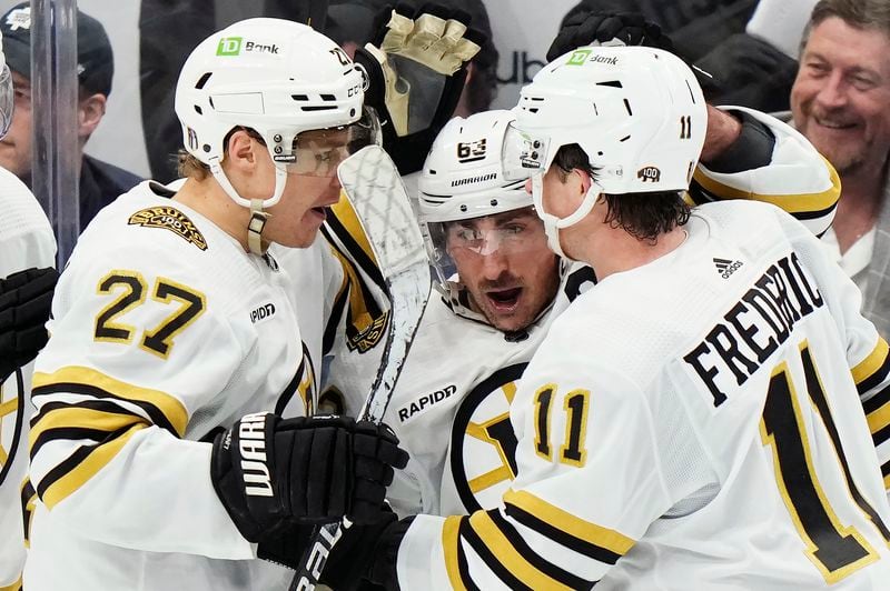 Boston Bruins' Trent Frederic (11) celebrates his goal against the Toronto Maple Leafs with Hampus Lindholm (27) and Brad Marchand during the second period of action in Game 3 of an NHL hockey Stanley Cup first-round playoff series in Toronto on Wednesday, April 24, 2024. (Frank Gunn/The Canadian Press via AP)