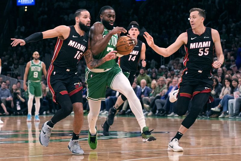 Boston Celtics guard Jaylen Brown, center, drives to the basket between Miami Heat's Caleb Martin (16) Duncan Robinson (55) during the first half of Game 2 of an NBA basketball first-round playoff series, Wednesday, April 24, 2024, in Boston. (AP Photo/Charles Krupa)