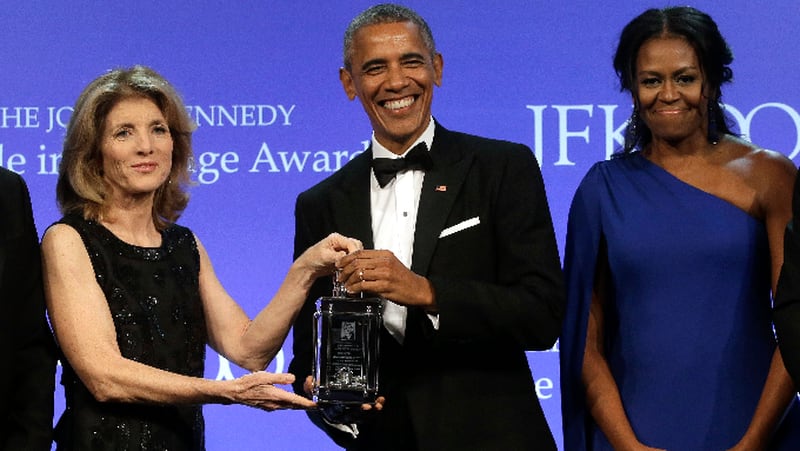 Former President Barack Obama, center, is presented with the 2017 Profile in Courage award by former U.S. Ambassador to Japan Caroline Kennedy, left, as former first lady Michelle Obama, right, looks on during ceremonies at the John F. Kennedy Presidential Library and Museum, Sunday, May 7, 2017, in Boston. (AP Photo/Steven Senne)