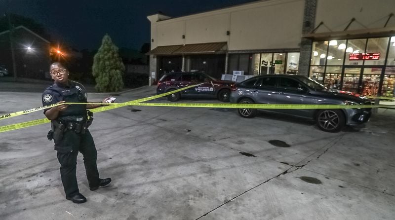 An officer stands at a crime scene outside a convenience store at the corner of Windsor and Fulton streets, where a woman was shot multiple times Wednesday morning. The shooting was one of six reported in Atlanta overnight.