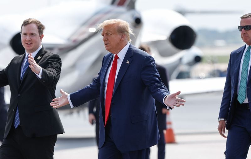 U.S. House candidate Brian Jack, left, walks with former President Donald Trump (center) at Hartsfield-Jackson International Airport on Wednesday.