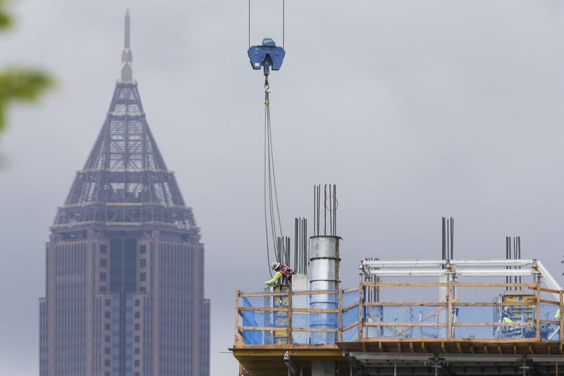 Construction workers work next to Ponce City Market with Bank of America Plaza seen in the background during an overcast day on Tuesday, July 12, 2022, in Atlanta. (Chris Day/Christopher.Day@ajc.com)