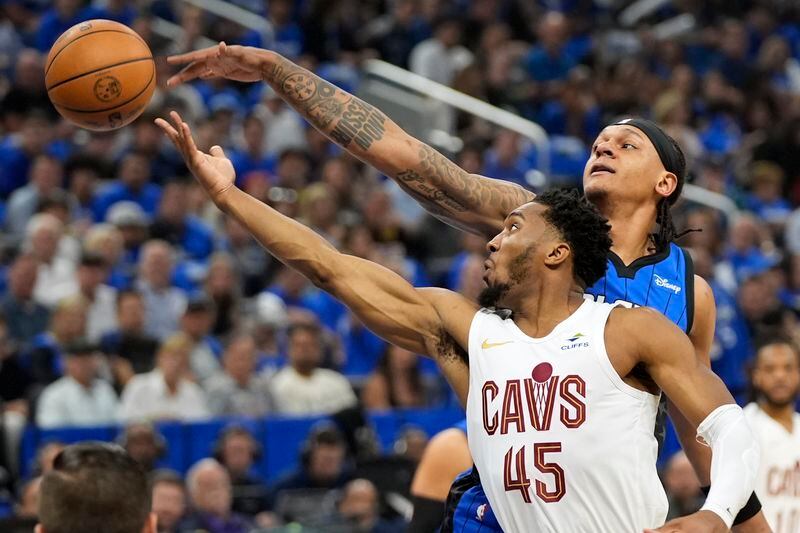 Cleveland Cavaliers guard Donovan Mitchell (45) and Orlando Magic forward Paolo Banchero, right, go after a rebound during the first half of Game 6 of an NBA basketball first-round playoff series, Friday, May 3, 2024, in Orlando, Fla. (AP Photo/John Raoux)