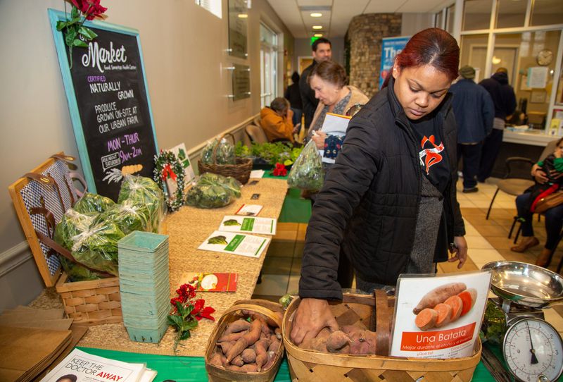 Anileidi Gomez (right) elects a sweet potato at a reduced price at the Market in the lobby of the Good Samaritan Health Center in Atlanta. CONTRIBUTED BY PHIL SKINNER
