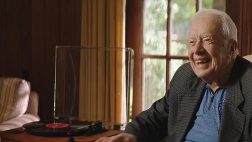 Former president Jimmy Carter smiles as he listens to an old LP.