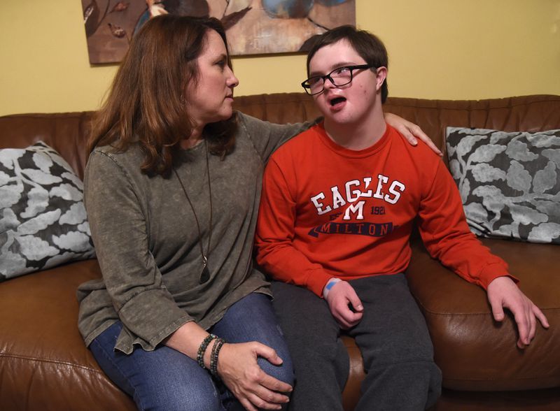 Heidi Moore and her son Jacob in their Alpharetta home on the day after the Texas court ruling on the Affordable Care Act. Jacob, who has Down Syndrome and autism and is a cancer survivor, has 15 specialty doctors. He just turned 18 and Moore is having a hard enough time transitioning him to adult specialty doctors; if he were on Medicaid, she says, it would be nearly impossible to find specialists. Under the ACA, she and her husband can keep him on their insurance until he’s 26, and the company can’t deny him coverage for his pre-existing conditions. (Photo by Annie Rice/For the AJC)
