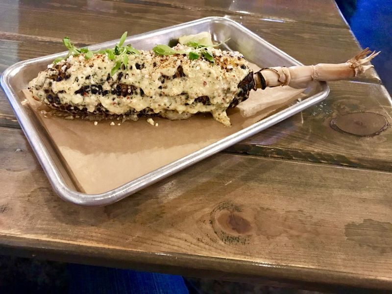 The elote at Mouth of the South sees grilled corn slathered with Duke’s mayo followed by a sprinkling of cotija cheese and chili powder. LIGAYA FIGUERAS / LFIGUERAS@AJC.COM