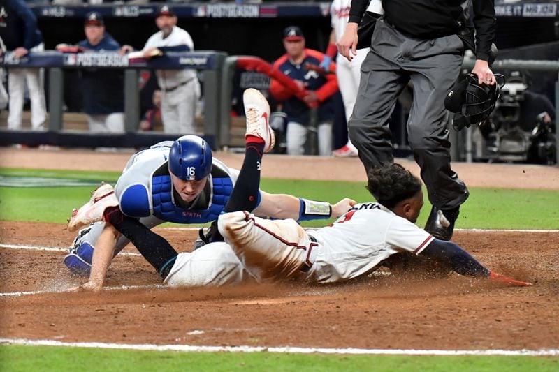 Braves second baseman Ozzie Albies (1) slides into home plate to score the game-tying run ahead of the tag of Los Angeles Dodgers catcher Will Smith during the eighth inning pf Game 2 of the NLCS Sunday, Oct. 17, 2021, at Truist Park in Atlanta. (Hyosub Shin / Hyosub.Shin@ajc.com)