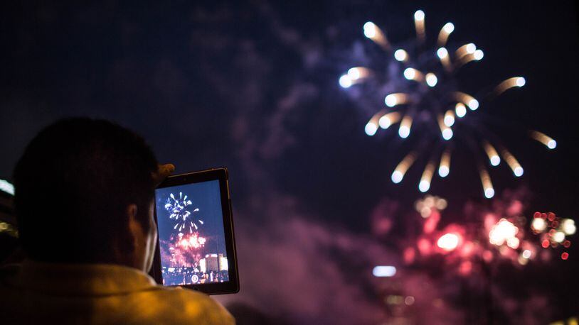 A man records a fireworks show on his iPad at Lenox Square during the annual July 4th event in 2015.