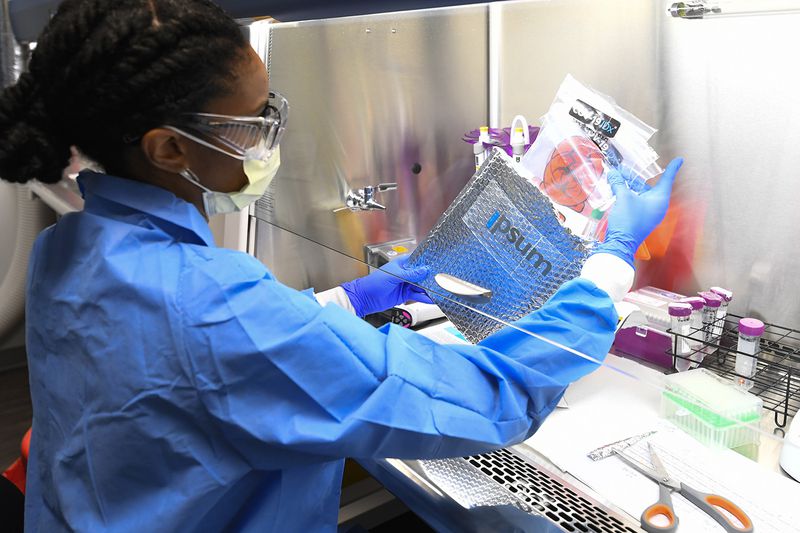 Molecular Biologist Leah Roberts gets a delivery of COVID-19 samples from a local practice ready for testing at Ipsum Diagnostics labratory on Monday, March 23, 2020.  (John Amis)