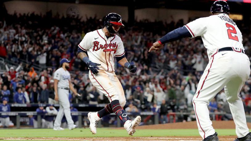 Braves leftfielder Eddie Rosario reacts after hitting the walk-off single as first base coach Eric Young Sr. (2) directs Rosario to touch first base in the ninth inning of Game of the NLCS against the Los Angeles Dodgers Sunday, Oct. 17, 2021, at Truist Park in Atlanta. The Braves won 5-4 to take a 2-0 lead in the series. (Curtis Compton / curtis.compton@ajc.com)