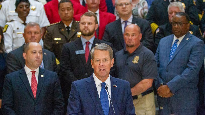 Gov. Brian Kemp, shown with law enforcement officials standing behind him at a press conference Monday at the Capitol, announced that first responders in the state will receive $1,000 bonuses. The money will come from a COVID-19 relief package that Democrats in Congress approved in March. STEVE SCHAEFER FOR THE ATLANTA JOURNAL-CONSTITUTION
