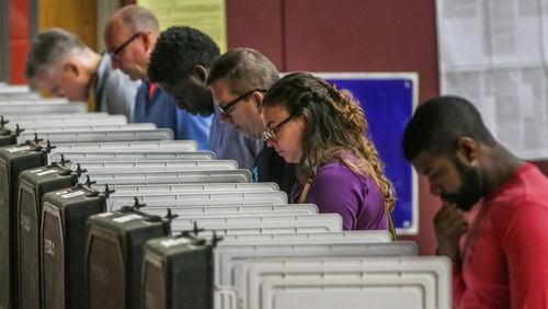 In this file photo, voters ponder May primary ballots at Henry W. Grady High School in Atlanta.  JOHN SPINK/JSPINK@AJC.COM