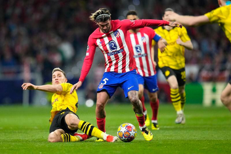 Atletico Madrid's Rodrigo De Paul, centre, challenges for the ball with Dortmund's Nico Schlotterbeck, left, during the Champions League quarterfinal soccer match between Atletico Madrid and Borussia Dortmund at the Metropolitano stadium in Madrid, Spain, Wednesday, April 10, 2024. (AP Photo/Manu Fernandez)