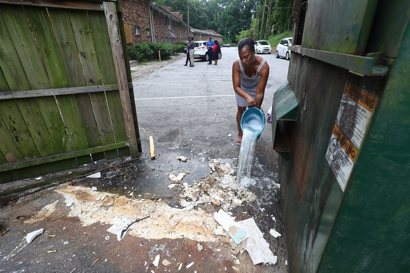 Resident Danielle Russell pours bleach over raw sewage that spilled from a discarded toilet left in the parking lot near her Pavilion Place apartment in August 2022. That day, Atlanta officials conducted a complexwide inspection of conditions, which led to a prosecution of its owner on dozens of code enforcement violations. (Curtis.Compton/Curtis Compton@ajc.com)