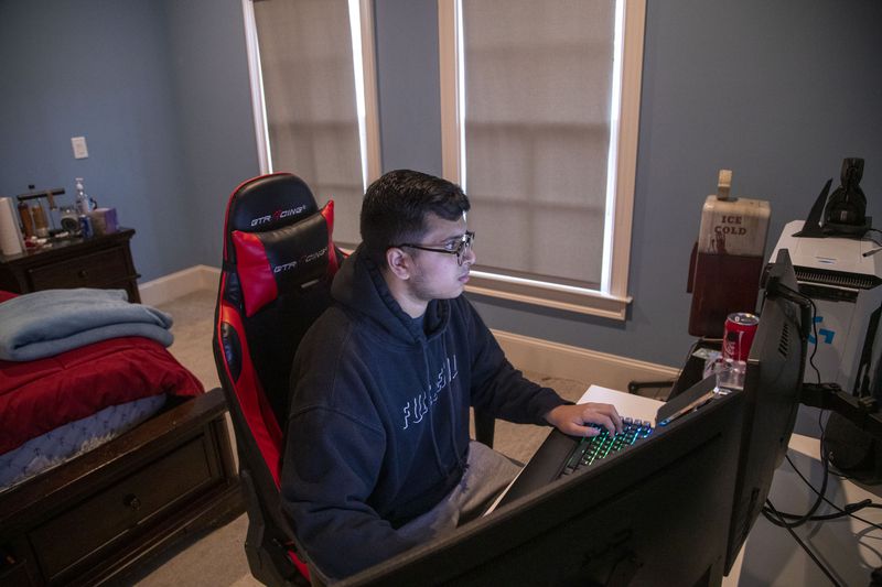 Peachtree Ridge High School senior Ahmad Yaqoob, 17 completes a digital learning task in his bedroom at his residence in Duluth on March 16, 2021. Yaqoob has been learning virtually since school let out in March 2020. (Alyssa Pointer / Alyssa.Pointer@ajc.com)
