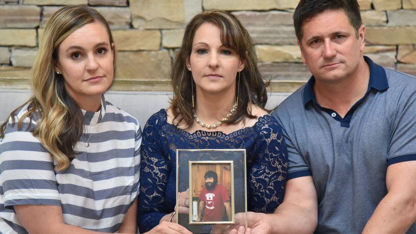 Siblings of Gregg Ivey, (from left) Brooke Levenson, Julie Ivey and Joe Ivey hold a photograph of their brother. Gregg Ivey who loved music and his dog River passed out, died of a heroin overdose in 2015. (HYOSUB SHIN / HSHIN@AJC.COM)