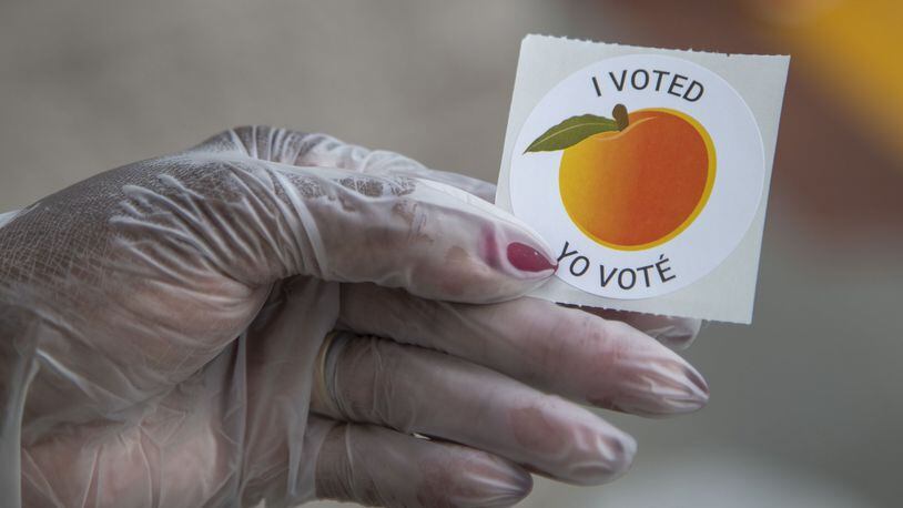 An early voter, who wore gloves to cast their ballot, shows off their sticker at the Gwinnett County Voter Registration and Elections Office in Lawrenceville, Monday, May 18, 2020. (ALYSSA POINTER / ALYSSA.POINTER@AJC.COM) AJC FILE PHOTO