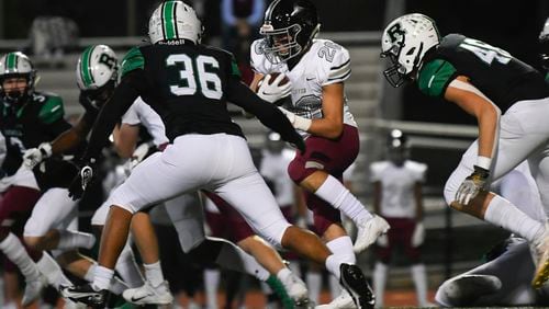 Friday Night football: Alpharetta's Jake Gil runs up the middle as Roswell's Riley Slaughter (36) moves in for the tackle during Friday's game.
