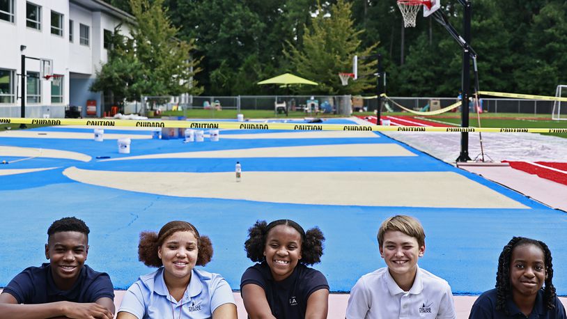 (Left to right) Christian Taylor,13; Paris Howard,13; Camille Harris,13; Wes Tilson,12 and Munachi Afulezi,13 take a photo in front of the SAE School basketball court on Thursday, August 25, 2022. Since June, the students have been recording temperatures of the school’s blacktop parking lot to determine if reflective paint will reduce the heat of the basketball court. (Natrice Miller/ natrice.miller@ajc.com).
