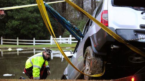 Officials remove an SUV that was submerged in a pond off Batesville Road in rural Cherokee County after its driver was rescued by firefighters near Atlanta National Golf Course early Monday morning, Dec. 29, 2014. The woman, who later died in a hospital, had called 911 on her cell phone, but rescuers were unable to find her in time. AJC FILE