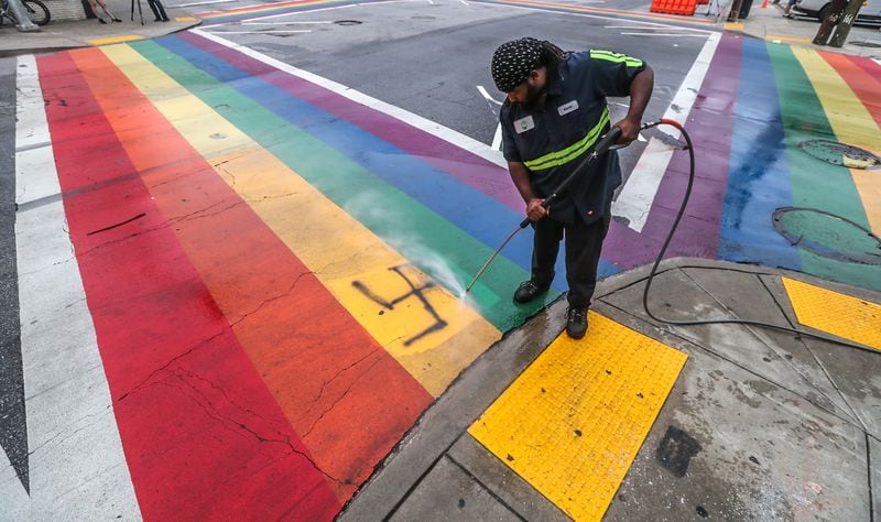 Jonathan Hurst with Midtown Alliance pressure washes spray paint from the rainbow crosswalk at 10th Street and Piedmont Avenue after it was vandalized early Friday morning.