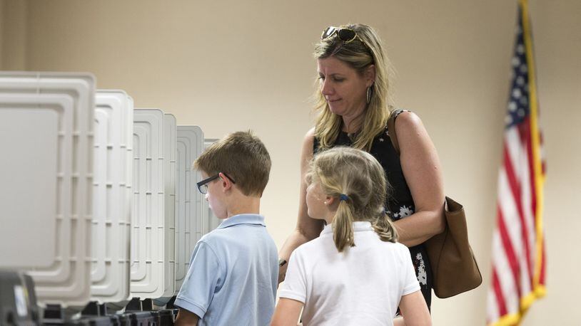 Dunwoody resident Kari Downing and her children Reagan and Thomas stand at a voting machine April 18 at the DeKalb County Public Library in Dunwoody during voting in the highly contested 6th Congressional District race. (DAVID BARNES / DAVID.BARNES@AJC.COM)