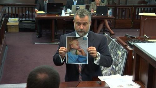 Defense attorney Maddox Kilgore, with a photo of a sleeping Cooper Harris, begins his cross-examination of lead investigator Phil Stoddard (back to camera) on Tuesday, Oct. 25, 2016. (screen capture via WSB-TV)