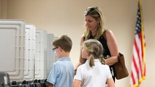 Dunwoody resident Kari Downing, center right, and her children Reagan, center right, and Thomas, center left, stand at a voting machine at DeKalb County Public Library in Dunwoody, on Tuesday, April 18, 2017. Cobb, Fulton and North DeKalb residents cast ballots for the highly contested 6th Congressional District race. (DAVID BARNES / DAVID.BARNES@AJC.COM)