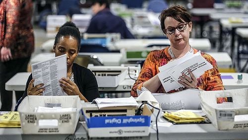 Elections Coordinator, Shantell Black (left) and Elections Deputy Director, Kristi Royston open and scan absentee ballots at the Voter Registration and Elections Office in Lawrenceville. JOHN SPINK/JSPINK@AJC.COM