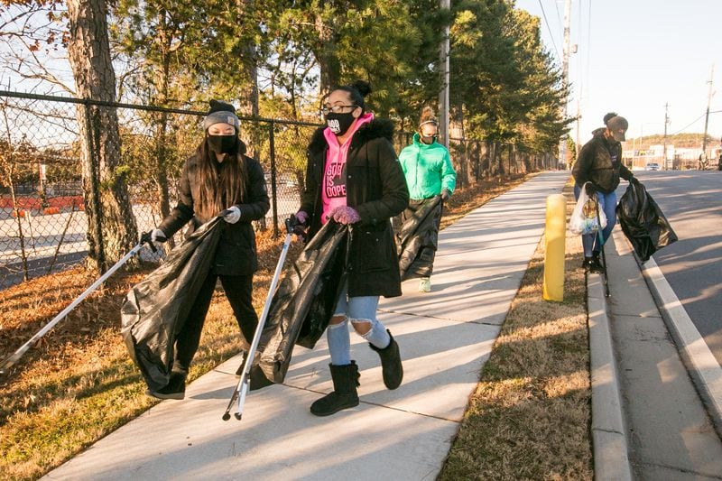 Volunteers, including Jennifer Lee, of Clarkston, from left, Misha McCleary, Lindsey Walton and Lauren Davis, pick up trash in the East Point community with the non-profit group Georgia STAND-UP on Martin Luther King, Jr. Day on Monday, Jan. 18, 2021.   (Jenni Girtman for The Atlanta-Constitution)