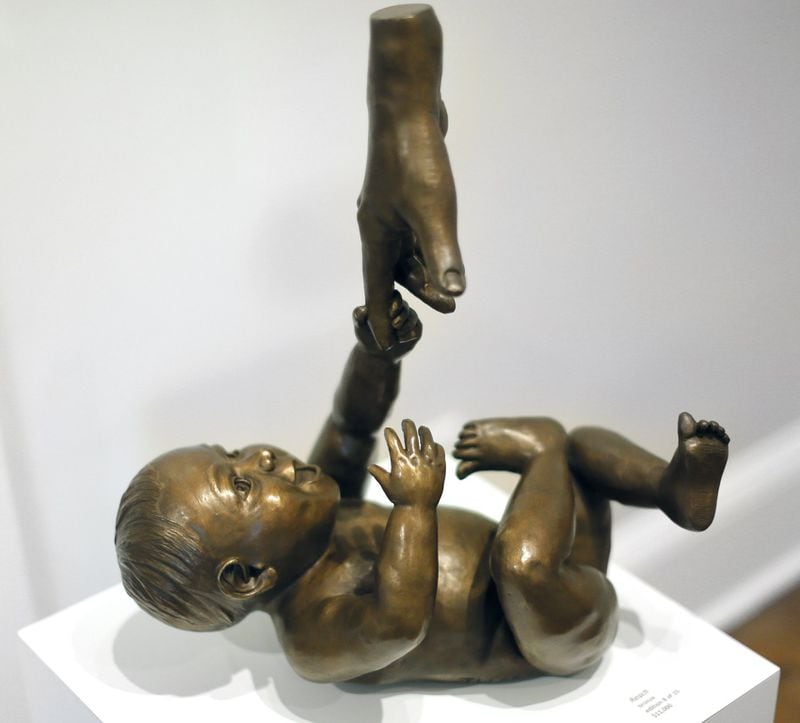 “Reach” is one of a trio of bronze baby sculptures by Atlanta sculptor Tom Williams, who has a one-man show at Spruill Gallery in Dunwoody. BOB ANDRES / BANDRES@AJC.COM