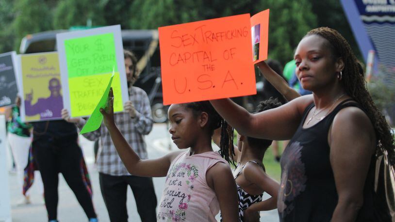 Arista Saunders, far right, and daughter Sanaz Saunders, 9, with other protesters outside Wolf Creek Amphitheater in College Park for the R. Kelly concert on Friday, Aug. 25, 2017.