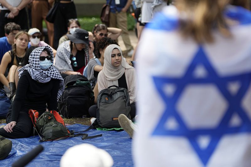 FILE - A student wrapped in and Israeli flag listens to Pro-Palestinian protesters gathered on campus at the University of Texas at Austin, Tuesday, April 30, 2024, in Austin, Texas. (AP Photo/Eric Gay, File )
