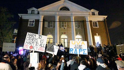 Protestors carry signs and chant slogans in front of the Phi Kappa Psi fraternity house at the University of Virginia, Saturday night, Nov. 22, 2014, in Charlottesville, Va. The protest, the most well-attended of several throughout the day, was in response to the university's reaction to an alleged sexual assault of a student revealed in a recent Rolling Stone article. (AP Photo/The Daily Progress, Ryan M. Kelly)