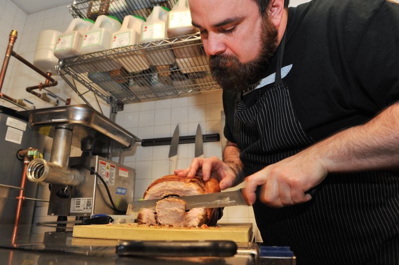 141229-ATLANTA-GA- Dine review of Todd Ginsbergs new counters Yalla and Fred's Meat & Bread, inside the Krog St Market, on Thursday January 1, 2015. Todd slices pork for the porchetta at Fred's Meat & Bread. (Beckysteinphotography.com) Todd Ginsberg cutting a porchetta at Fred's