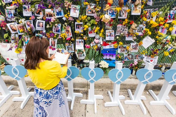 Terry Franco reads a book of Psalms in front of a makeshift memorial to people affected by the partial collapse of the Champlain Towers South condo, in Surfside, Fla., on Wednesday July 7, 2021. (Saul Martinez/The New York Times)