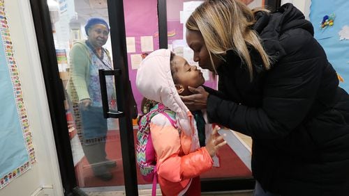 Rabiah Morning-Parker gives her daughter Ayana, 7, a kiss as she picks her up at Genesis Early Learning & Child Development Center with the center’s director Addie Lummus looking on Thursday, Jan. 21, 2021, in Atlanta. Morning-Parker is an Atlanta Public School teacher who returned to work in-person before her daughter’s school restarted in-person learning. Curtis Compton / Curtis.Compton@ajc.com