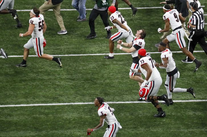 Georgia players, including  Georgia Bulldogs quarterback JT Daniels (18), storm the field after their victory at the 2022 College Football Playoff National Championship  between the Georgia Bulldogs and the Alabama Crimson Tide at Lucas Oil Stadium in Indianapolis on Monday, January 10, 2022.   Bob Andres / robert.andres@ajc.com