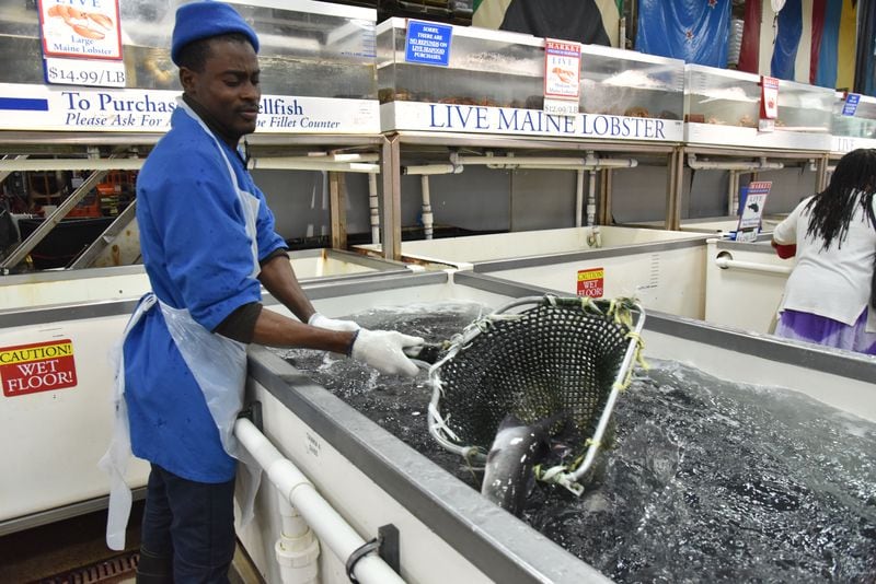 Kossivi Gnassou shows live fish. Customers can select Maine lobster, Dungeness crab, Blue crab, crawfish and catfish.