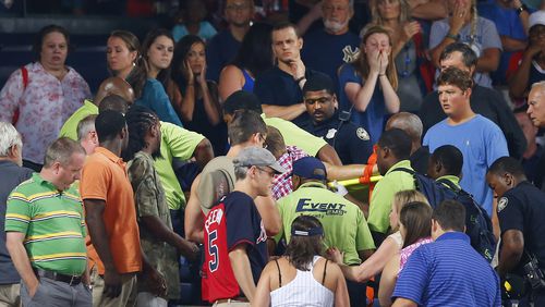 Rescue workers carry an injured fan from the stands at Turner Field during a game between Atlanta Braves and New York Yankees Saturday. The fan fell from the upper desk onto concrete and has died. (AP Photo/John Bazemore)